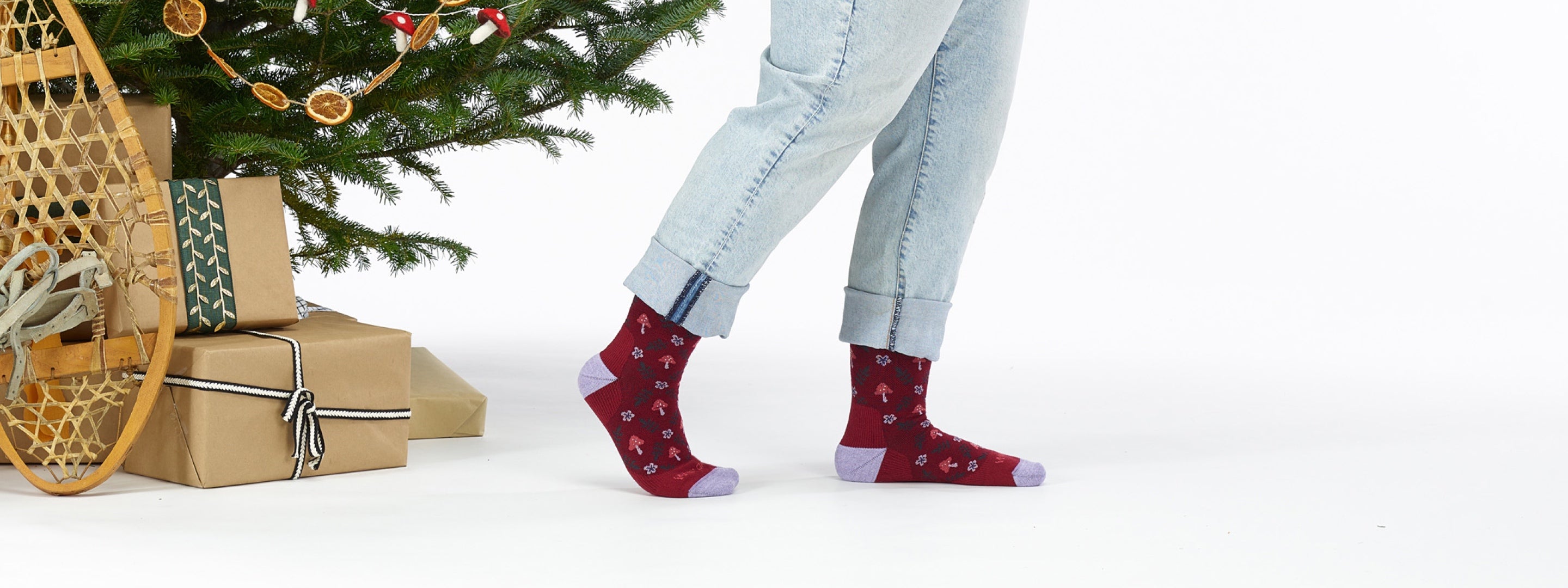 Close up of feet wearing clogs and burgundy socks with a floral and mushroom pattern