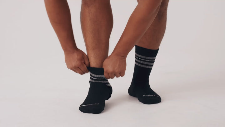 Model putting on, adjusting and standing in WIDE OPEN socks.