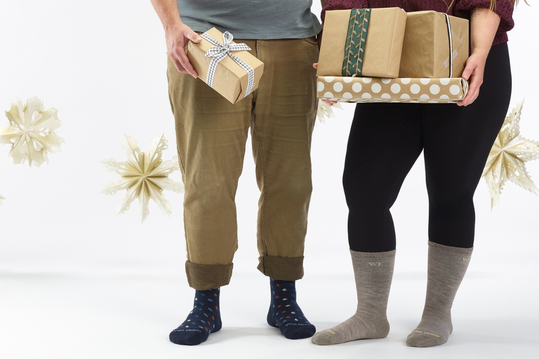 Man and woman's bodies from the waist down holding gifts against white background