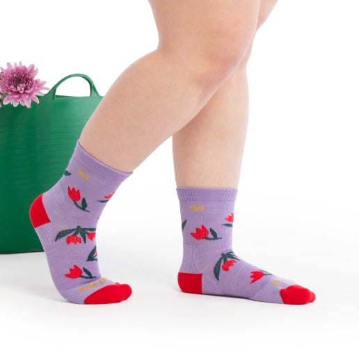 Feet wearing purple socks with a bright tulip pattern