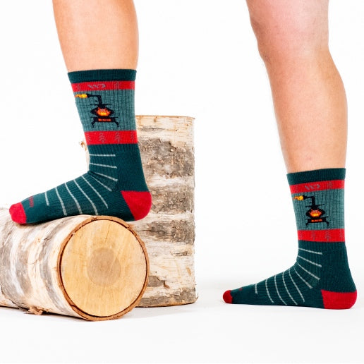 Feet wearing holiday socks - green with stripes and a blazing wood stove