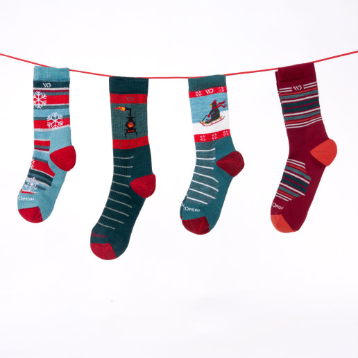 Four wide holiday socks hung up like stockings and showing off great winter designs