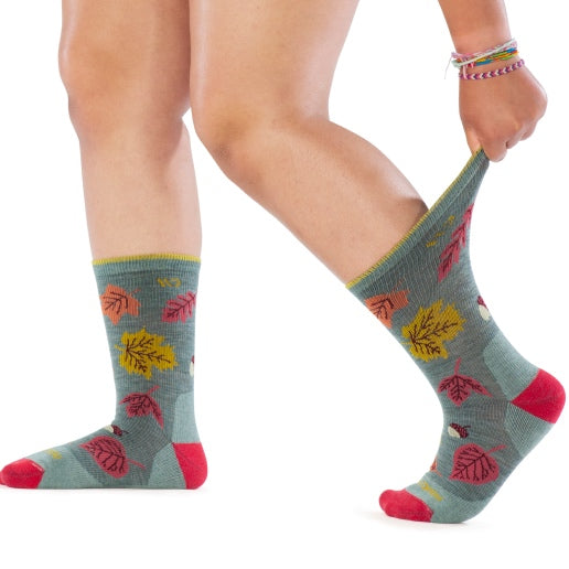 Person wearing new socks with an autumn leaf design, pulling the cuff to show stretch