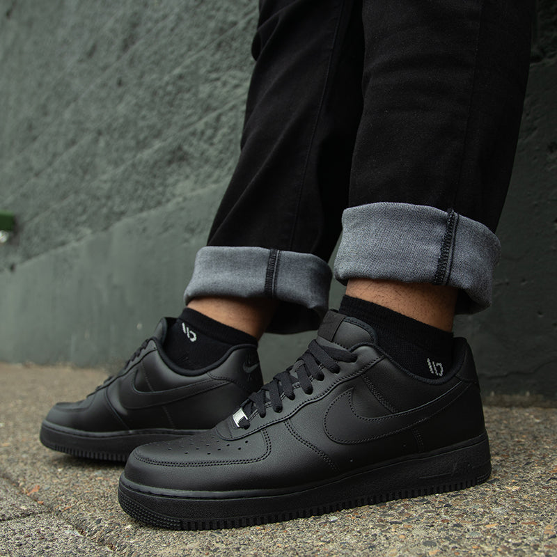 Mens' feet wearing black sneakers and black socks, a top selling style from Wide Open 