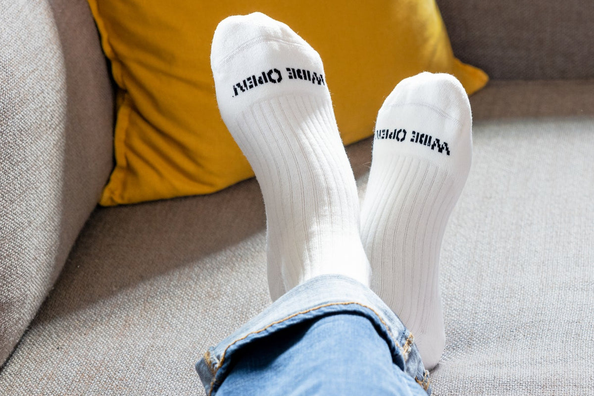 Model sitting on couch wearing wide open men's cushioned crew socks in white