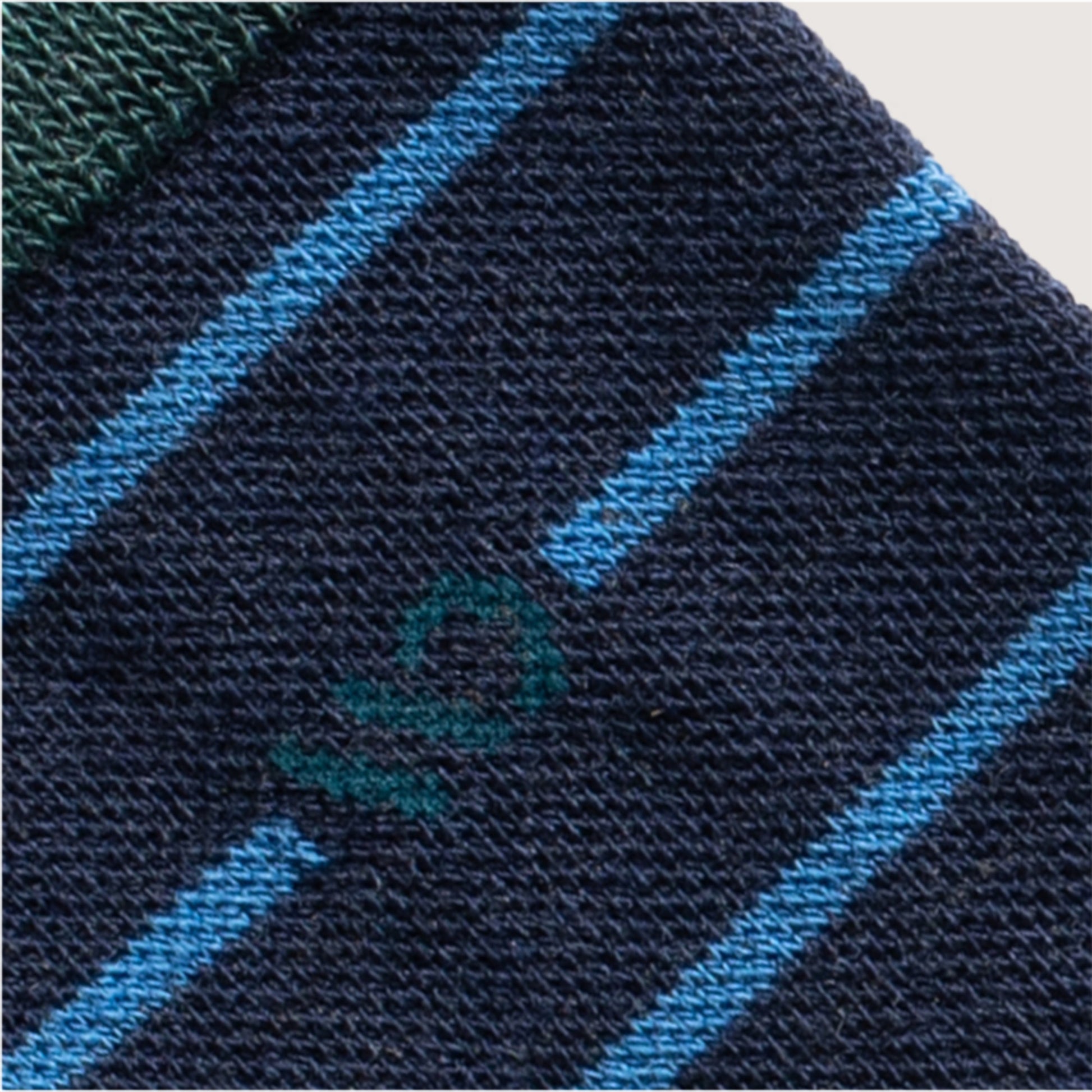 Detail featuring a dark teal logo with wide spaced blue stripe and denim body --Denim