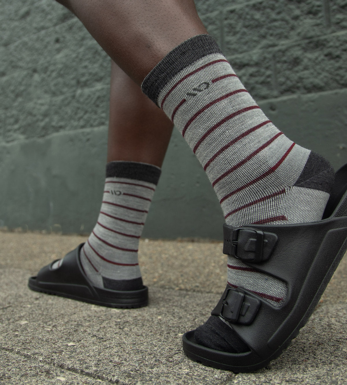 Feet walking outside in Men's Lightweight Horizontal Pinstripe Crew Socks and black sandals.