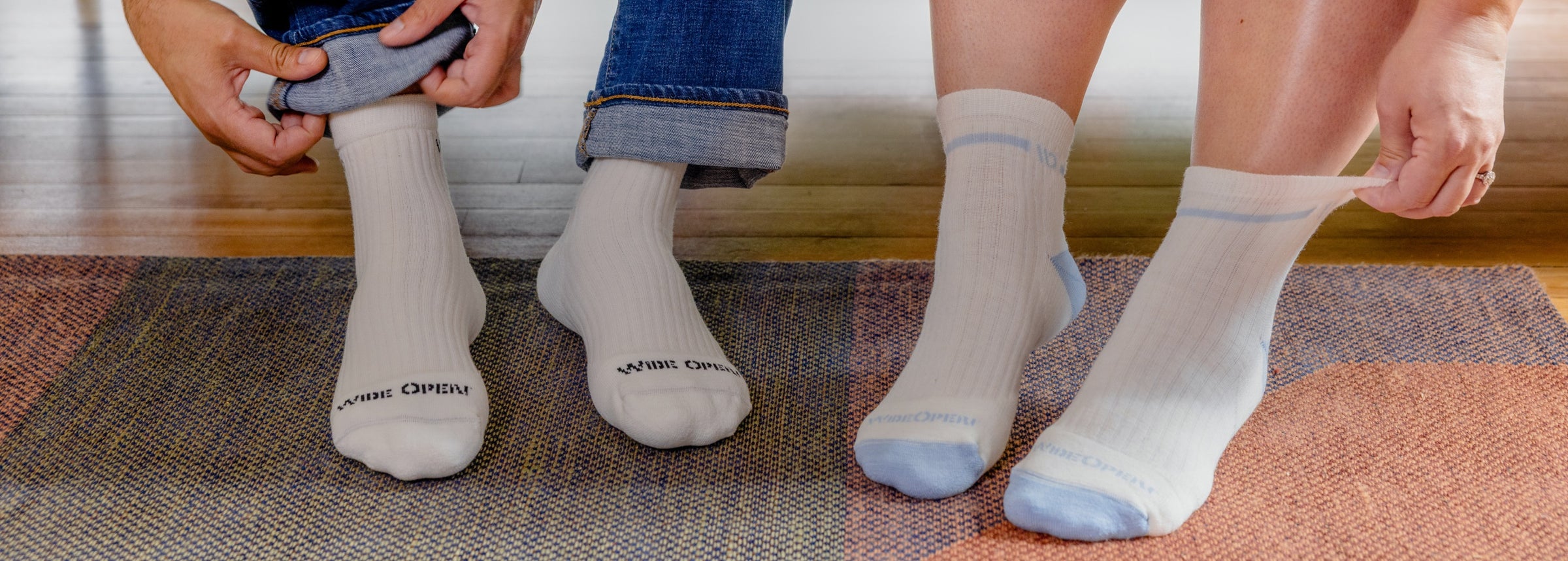 Two pairs of feet wearing white Merino Wool socks with a wide fit