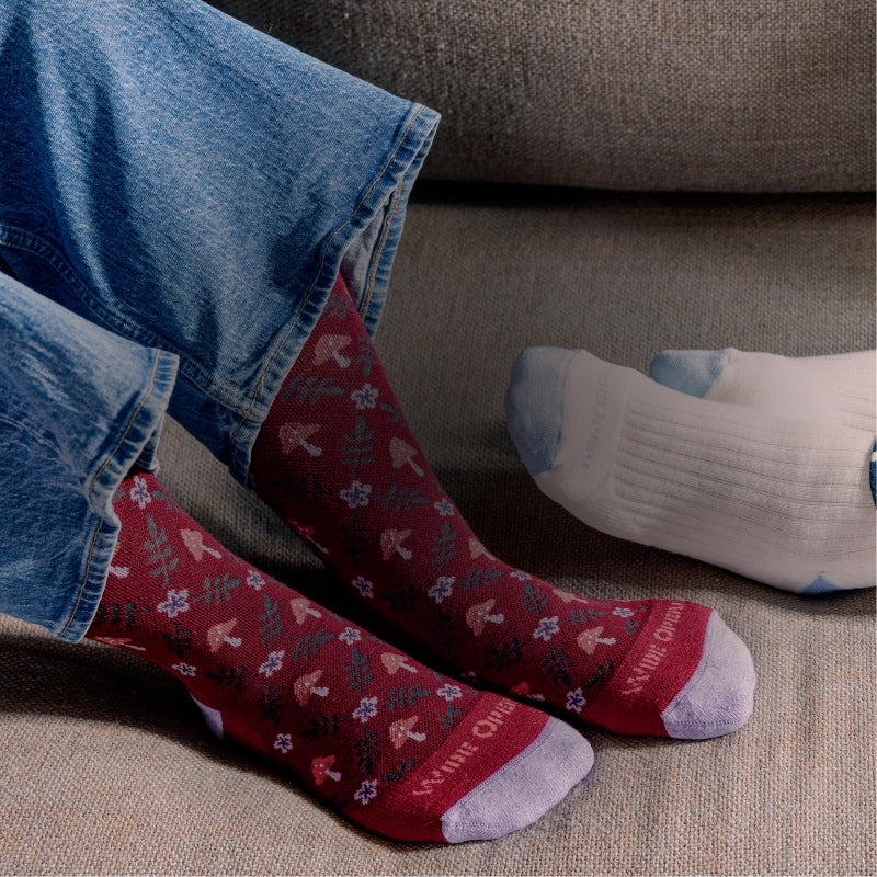 Two pairs of feet in wide width socks - white ones, and burgundy ones with mushrooms