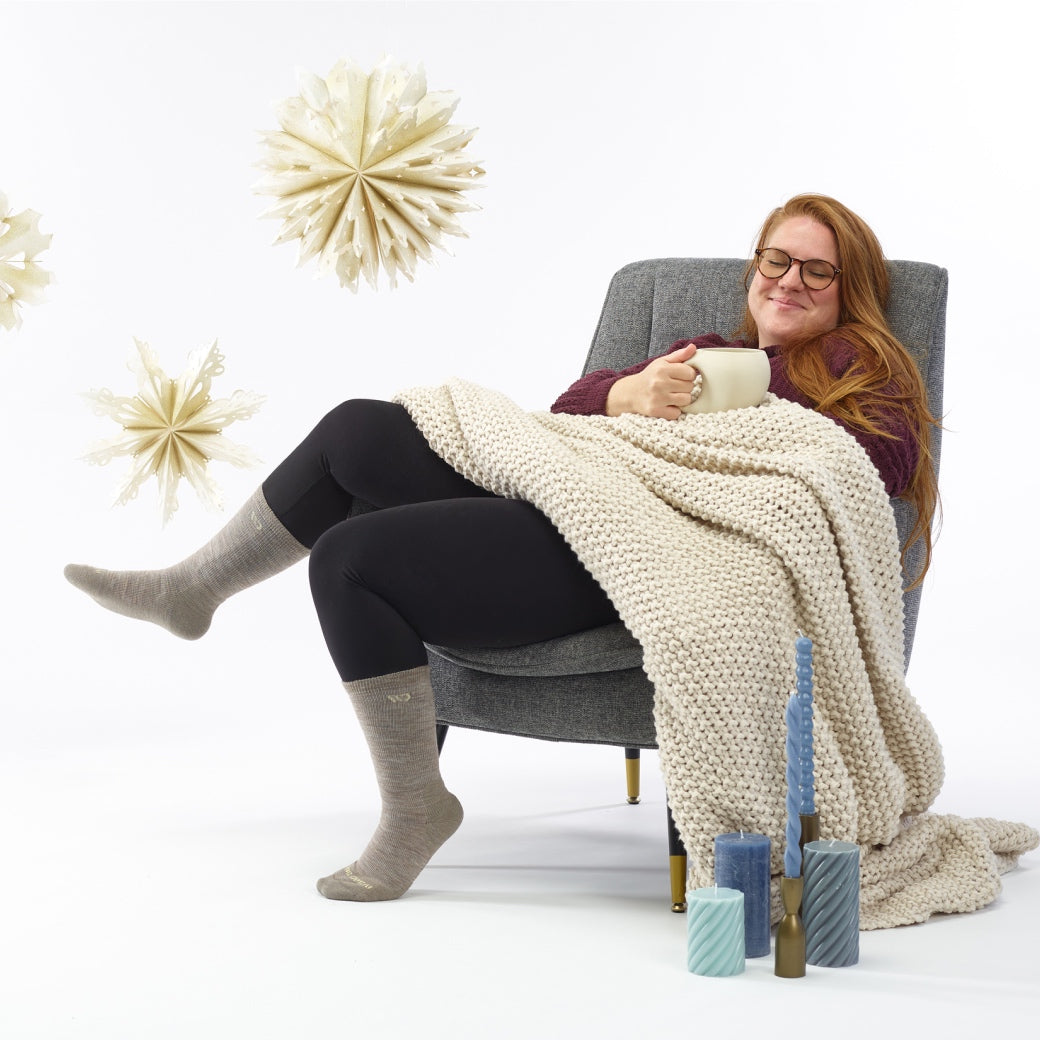 A woman with tea and a blanket looking very cozy in her Wide Open socks