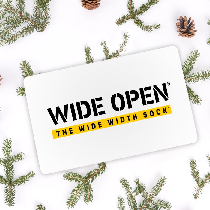 A Wide Open gift card laid out over some evergreen boughs