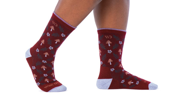 Feet wearing wide open socks covered in cute mushrooms and flowers