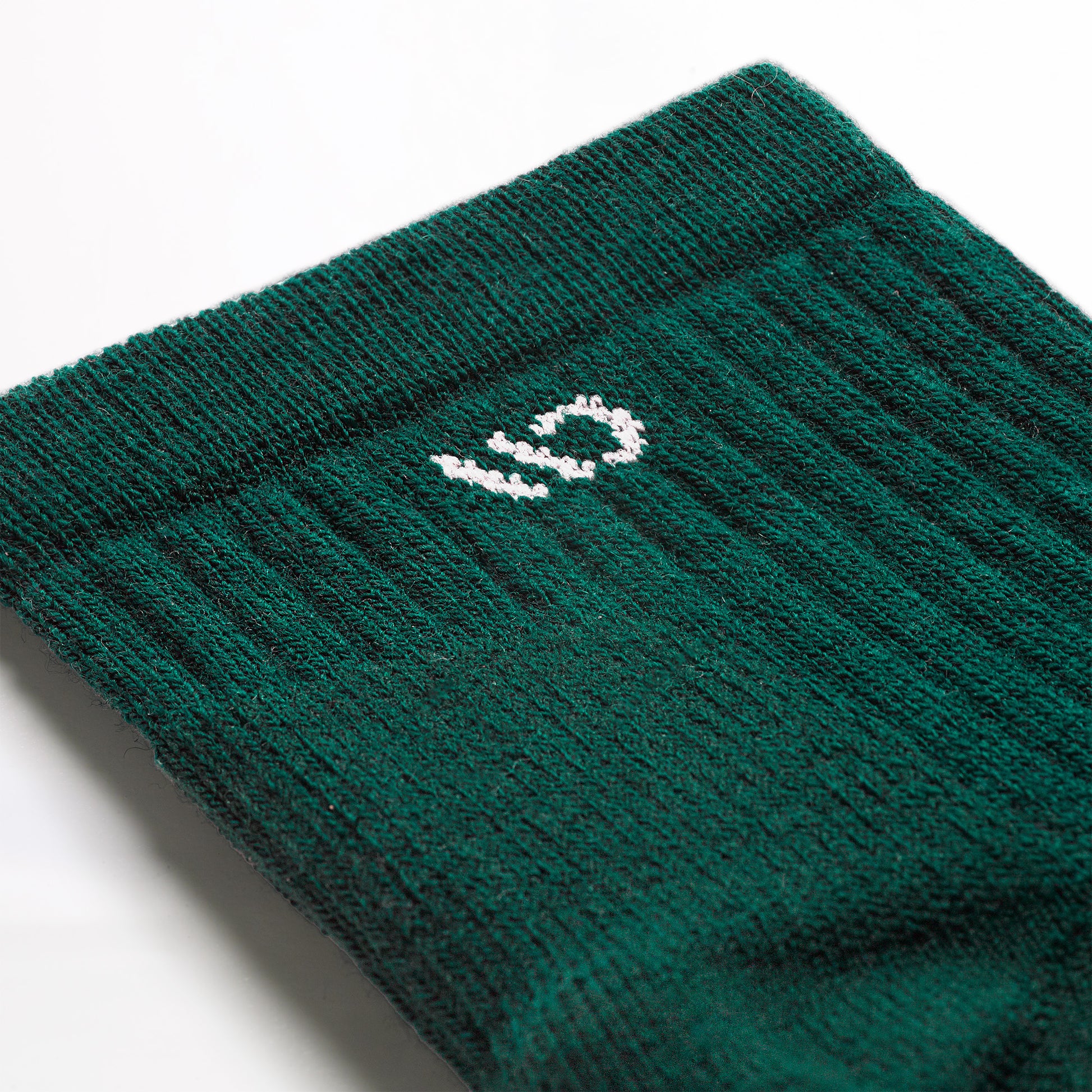 Detail image of the 9004 Solid Quarter sock in Spruce featuring the white logo on the cuff and green body