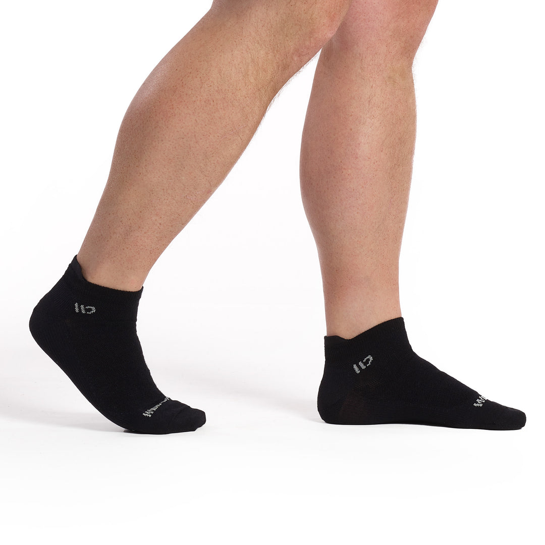 Model walking to the right wearing the 9013 solid lightweight ankle socks in black with gray logo 