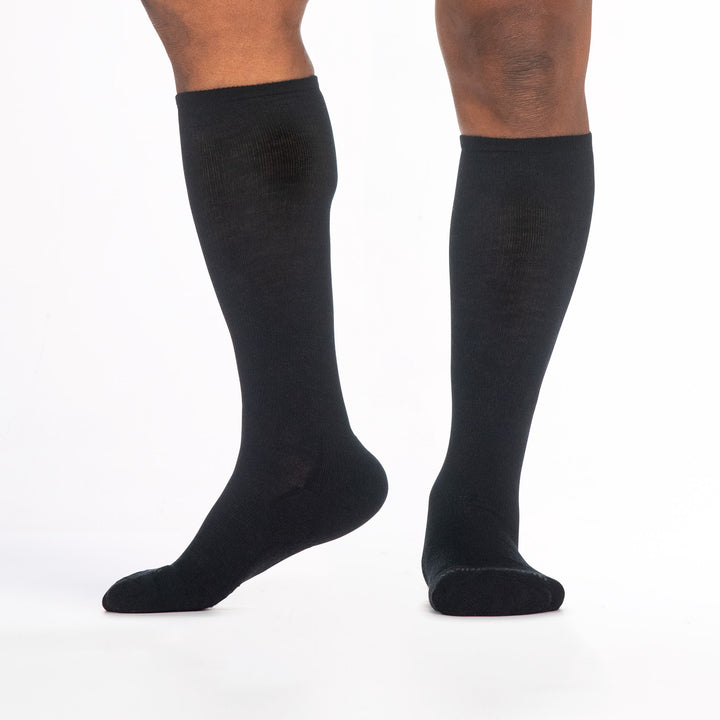 9017 black knee high sock with gray logo shown from side and front left foot to the side heel raised