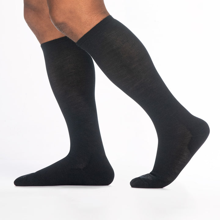 9017 black knee high sock with gray logo,  shown from the side feet pointing to the left with back heel raised