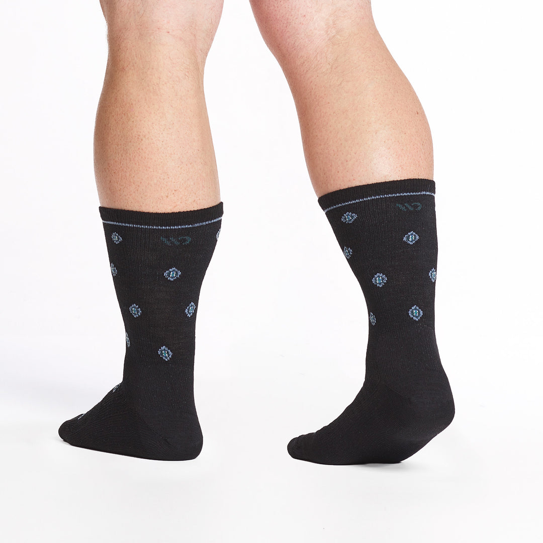 9018 black crew sock with dark teal logo, white geometric dots shown from behind with right heel raised