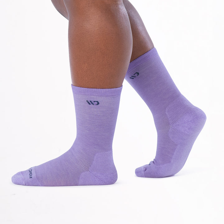 Model walking to the left with back foot lifted wearing the 9504 in lavender