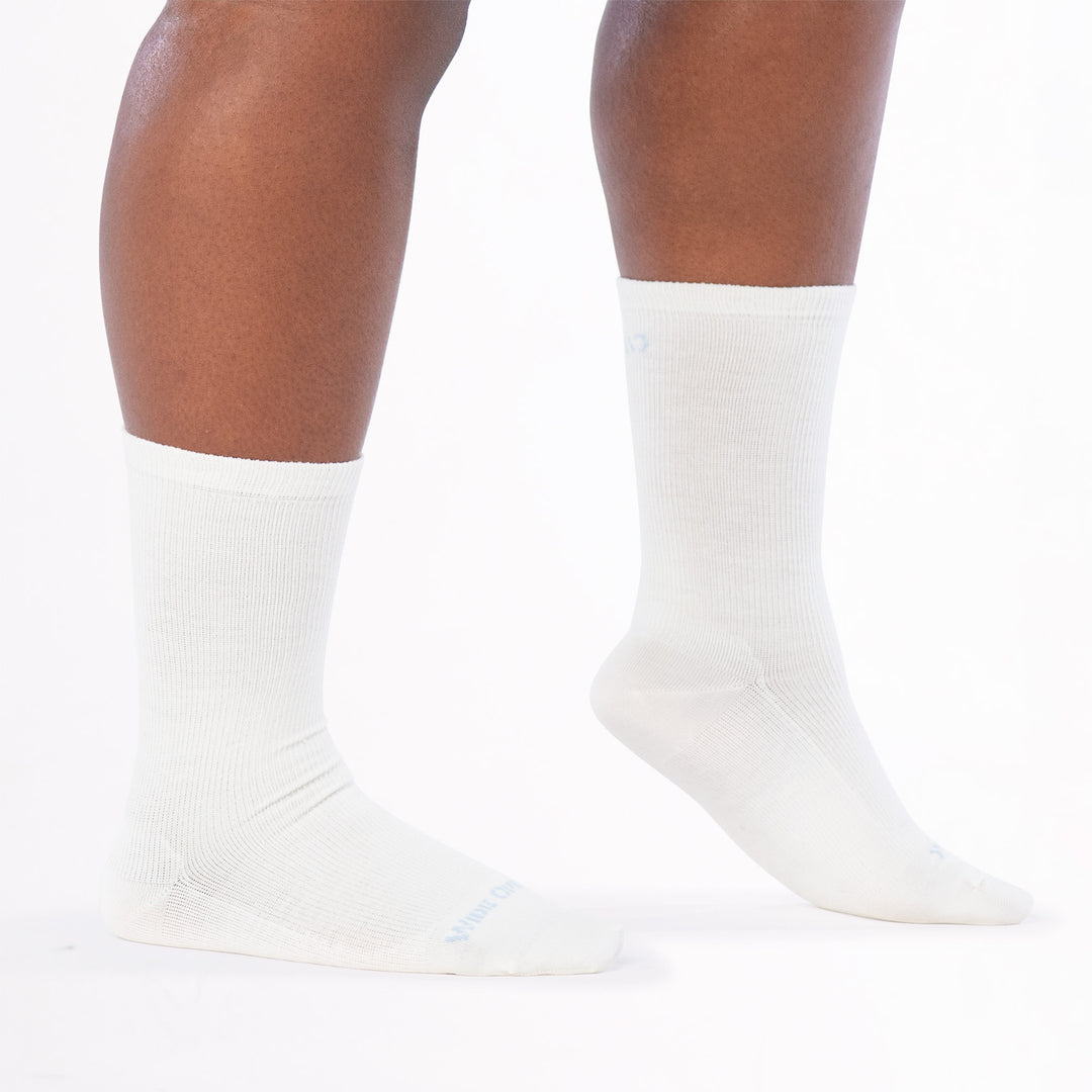 models feet to the right with front foot lifted on toes wearing the 9513 solid basic lightweight crew in white