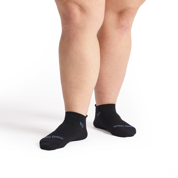 models feet facing forward wearing the 9514 solid lightweight ankle sock in black showing the logo on the toe