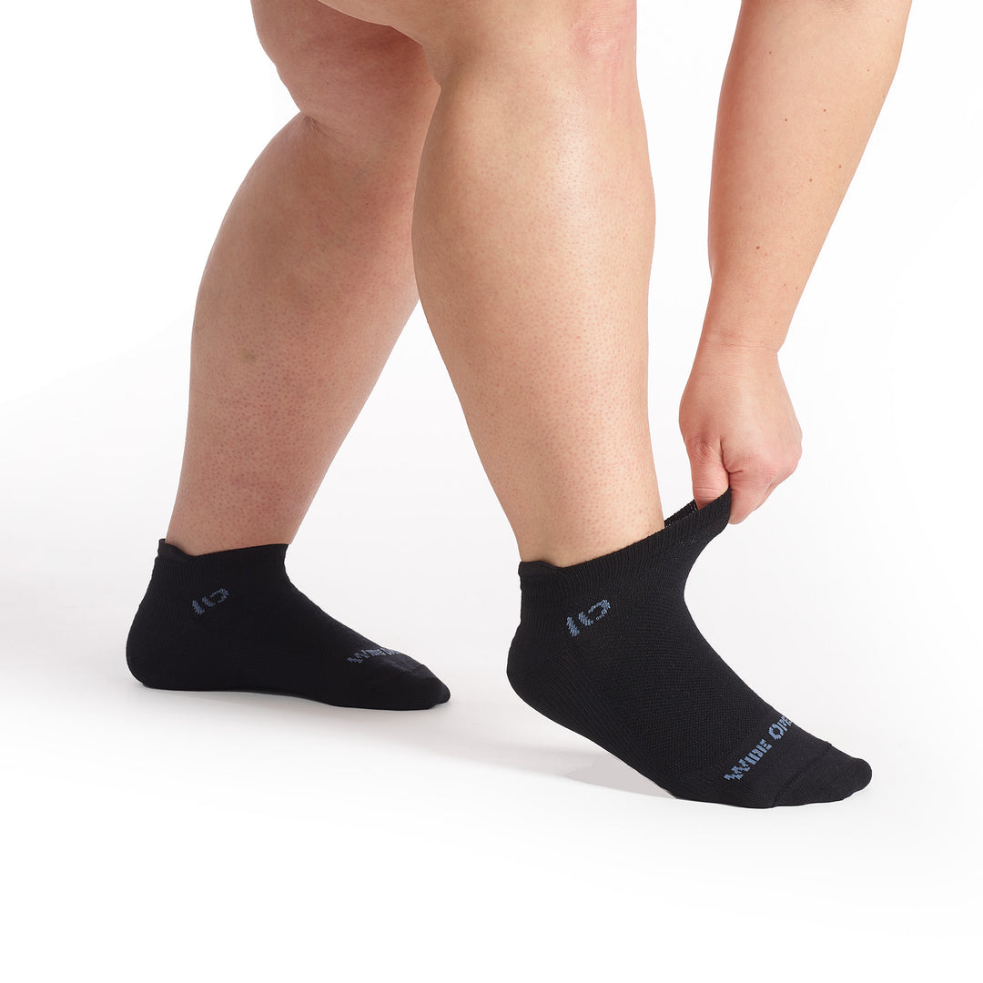 Models feet pointed to the right stretching the cuff on the 9515 solid lightweight ankle sock in black 