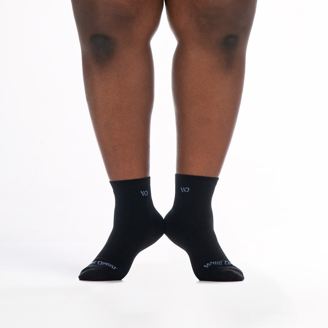 9515 black quarter sock with blue logo, shown from the front heels raised and touching 