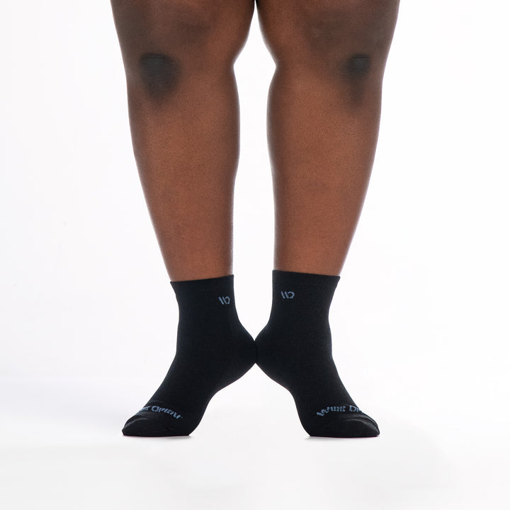9515 black quarter sock with blue logo, shown from the front heels raised and touching 