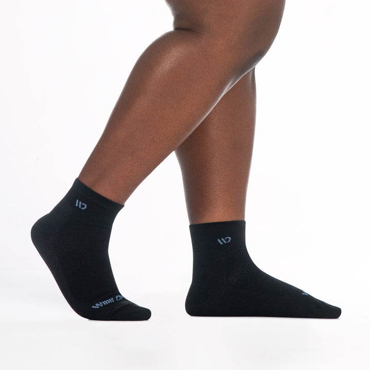 9515 black quarter sock with blue logo, shown from the side feet to the right back heel raised