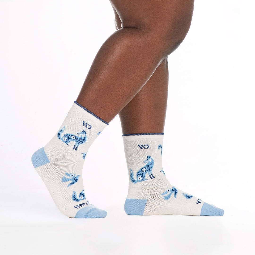 9516 white micro crew with lt blue heel/toe/design dark blue logo, shown from the side with back foot lifted
