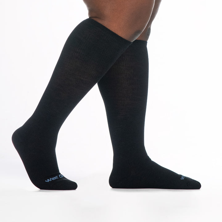 9517 black knee high sock with blue logo, shown from the side feet to the right back foot raised