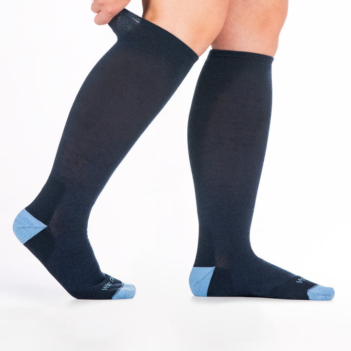 9517 denim knee high sock with light blue heel/toe/logo, shown from the side feet to the right back cuff being stretched