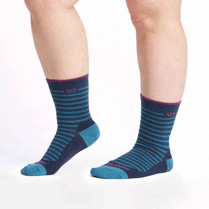 9518 - Navy crew sock with teal stripes, teal heel/toe, and magenta logo and cuff trim, Feet to the left with heel lifted