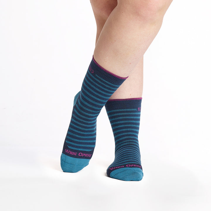 9518Navy crew sock with teal stripes, teal heel/toe, and magenta logo cuff trim, feet crossed.