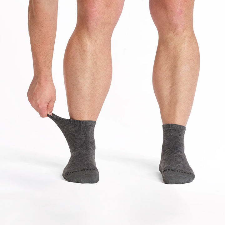 model stretching the cuff on his left foot wearing the 9014 lightweight quarter sock in gray 