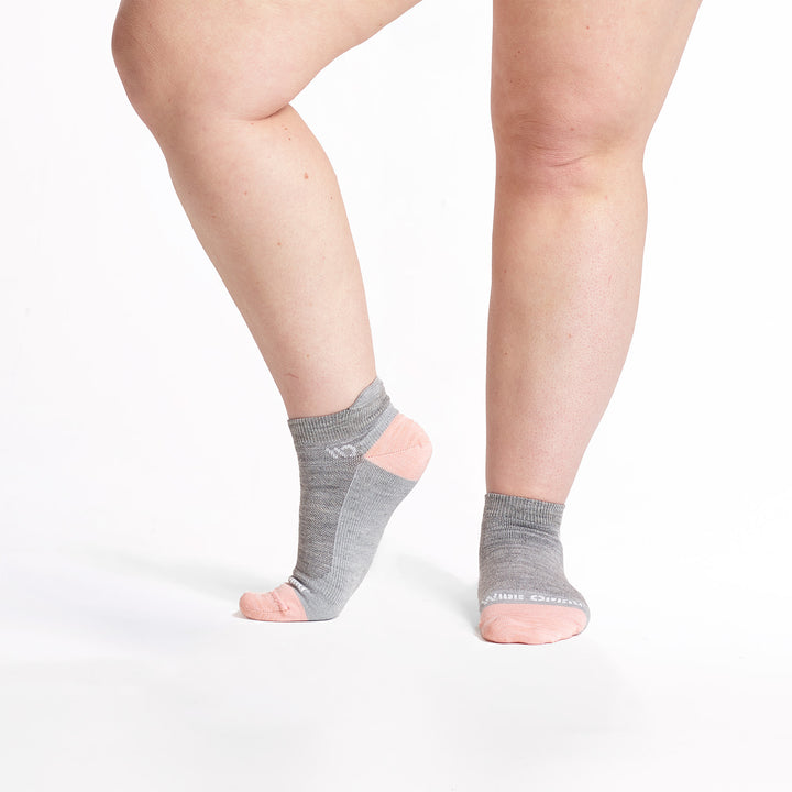 Models feet with left foot lifted wearing the 9514 lightweight ankle sock in light gray 