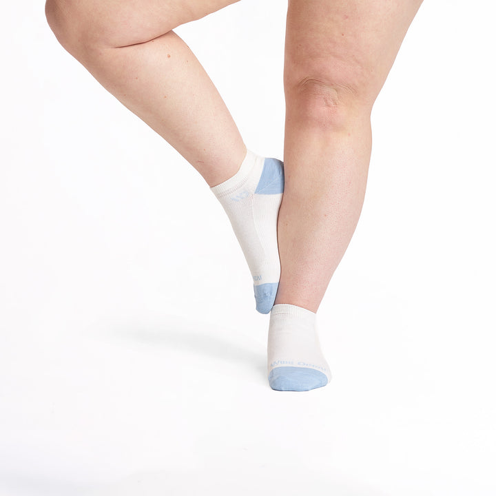 models feet with left foot lifted onto the right leg wearing the 9514 lightweight ankle sock in white