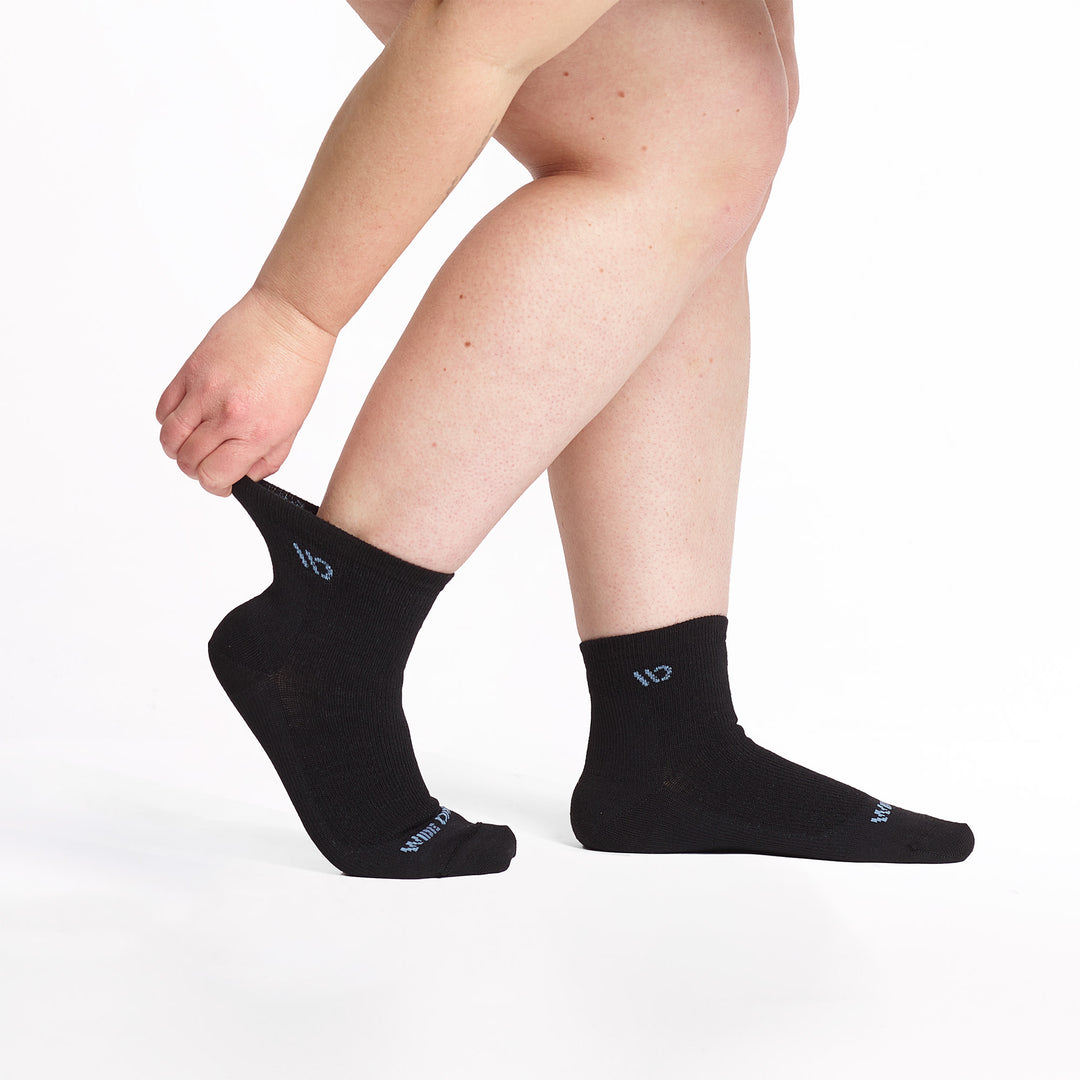 Model stretching the back sock wearing the 9515 lightweight quarter sock in black 