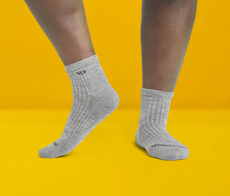 Feet in gray wide width socks against a fun yellow background