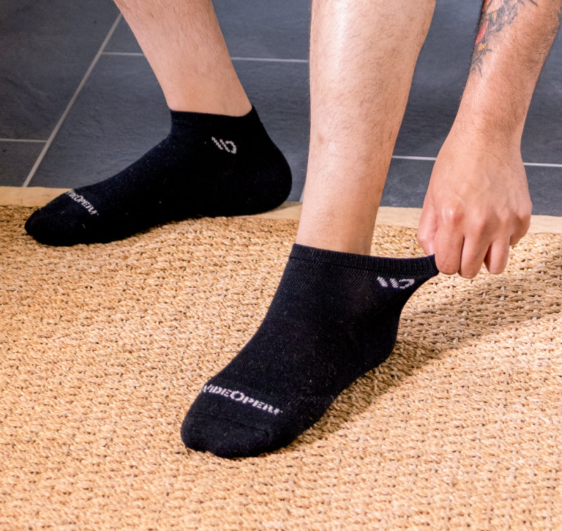 Model reaching down to stretch the ankle cuff of his wide open sock.