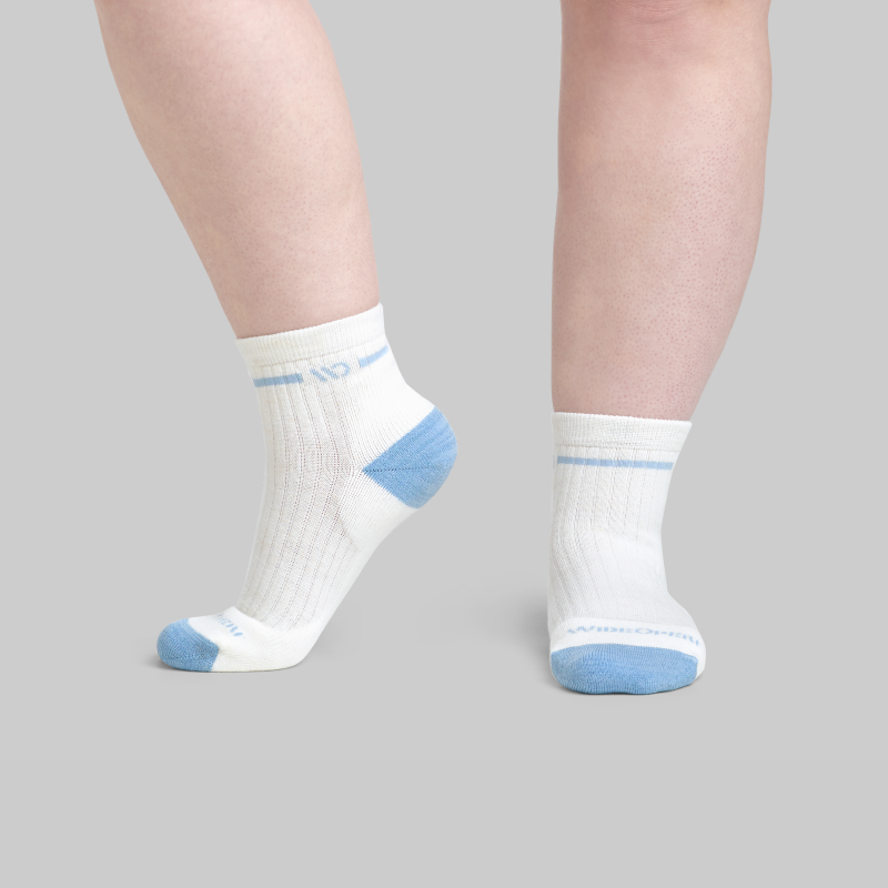A pair of wide feet wearing wide socks in white with blue heel and toes