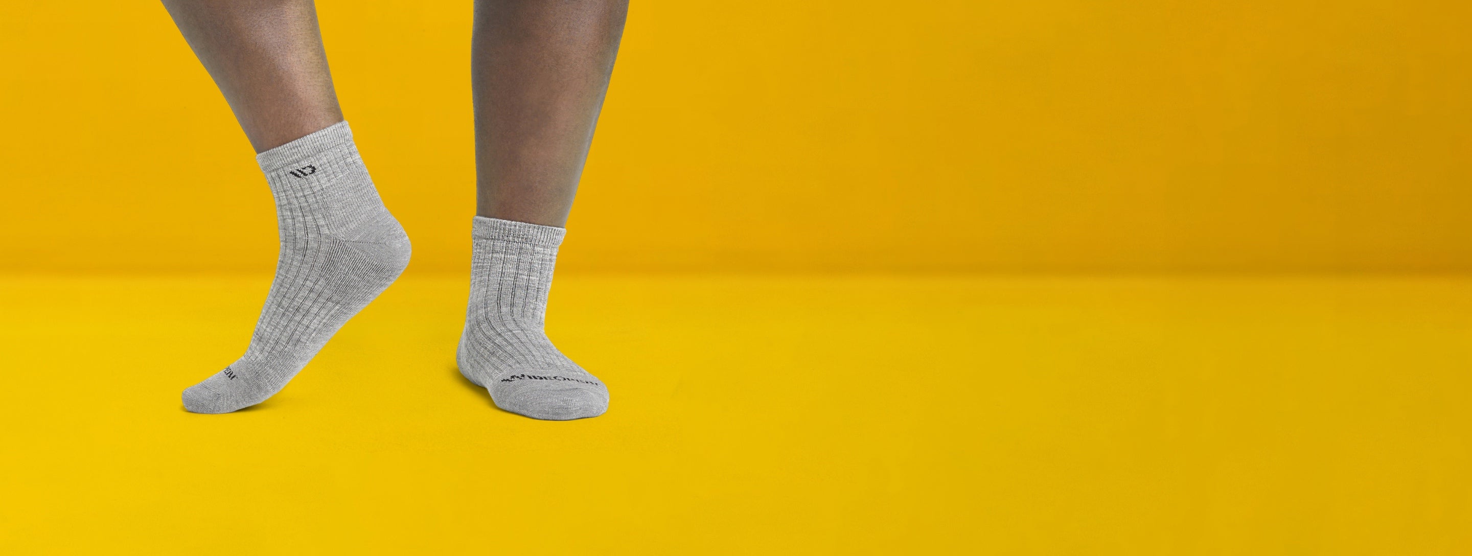 Feet in gray wide width socks against a fun yellow background