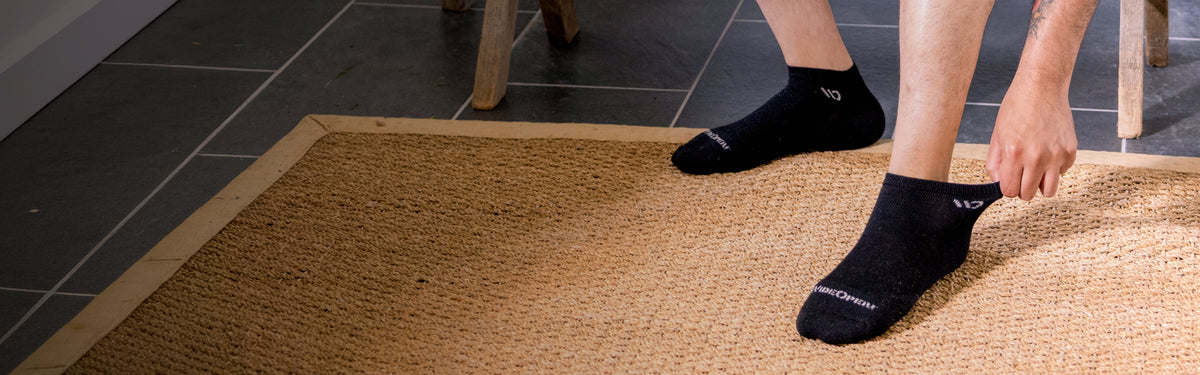 Model reaching down to stretch the ankle cuff of his wide open sock.