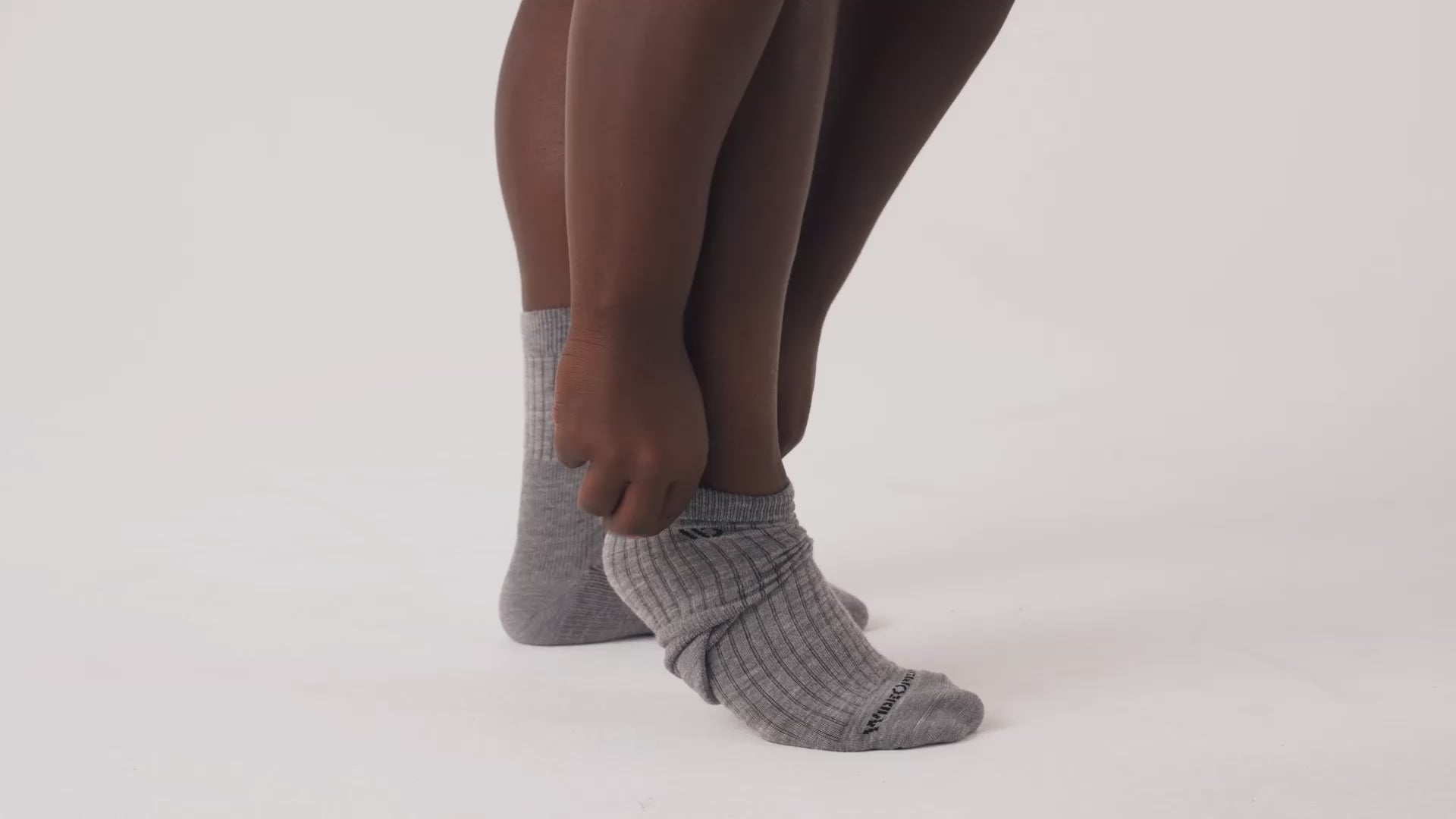 Model putting on, adjusting and standing in WIDE OPEN socks.