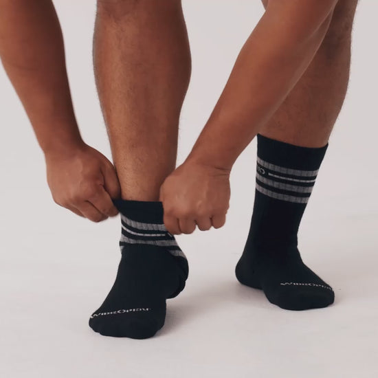 Model putting on, adjusting and standing in WIDE OPEN socks.